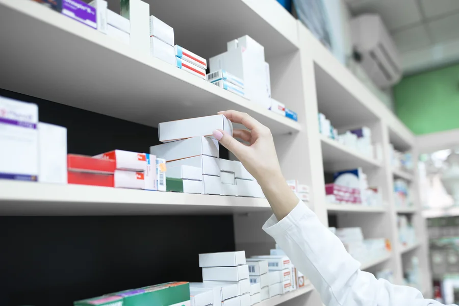 Apotheker nimmt Arzneimittelverpackung aus Regal